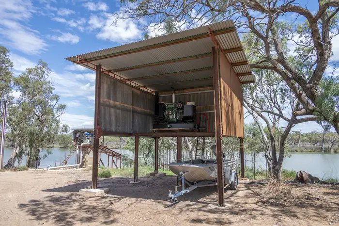 Open-sided pump and control shed raised on steel posts beside Big Toolunka Creek