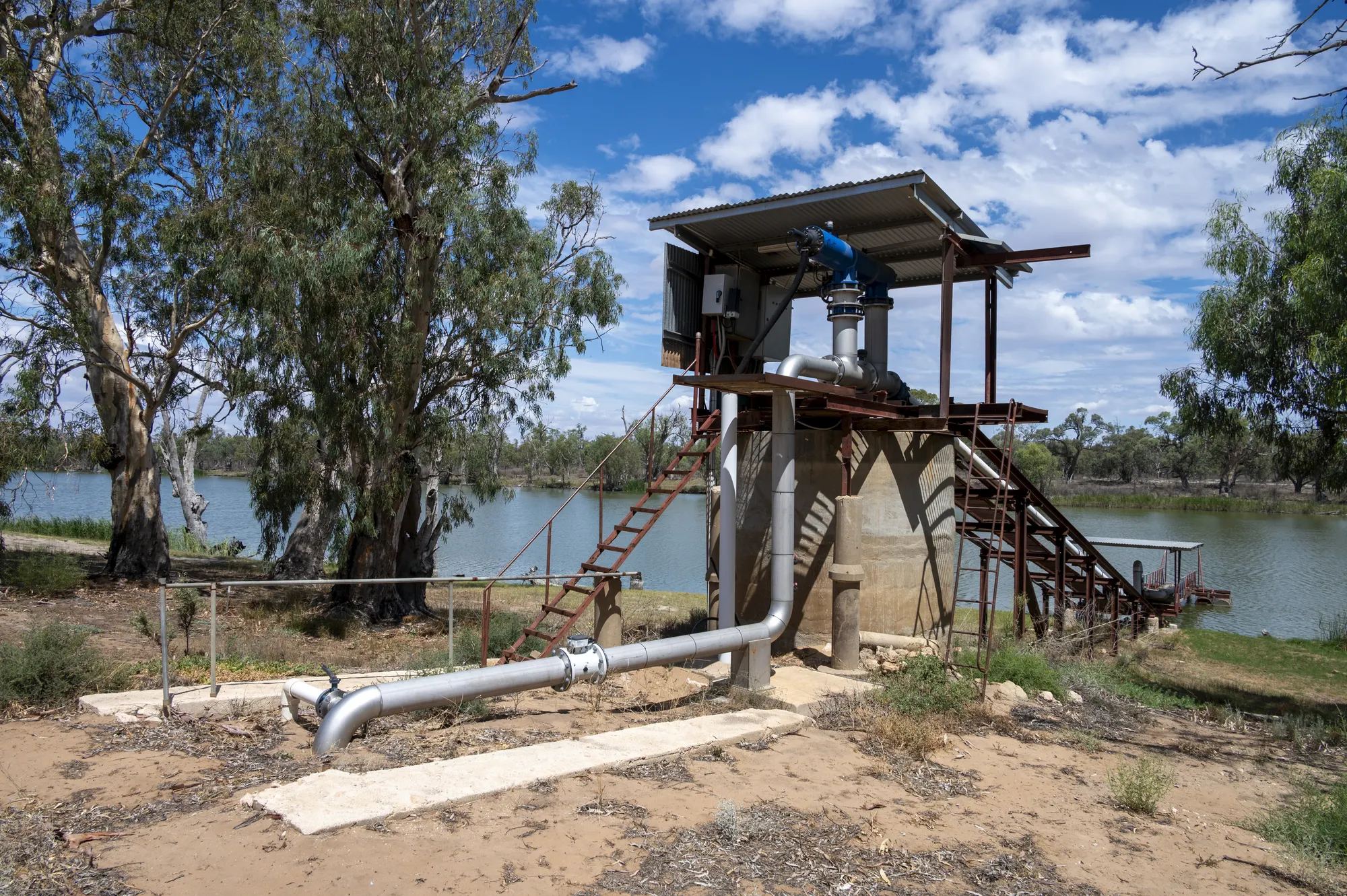 Commercial pumping station on a raised platform beside Big Toolunka Creek with steel pipeline at the water's edge
