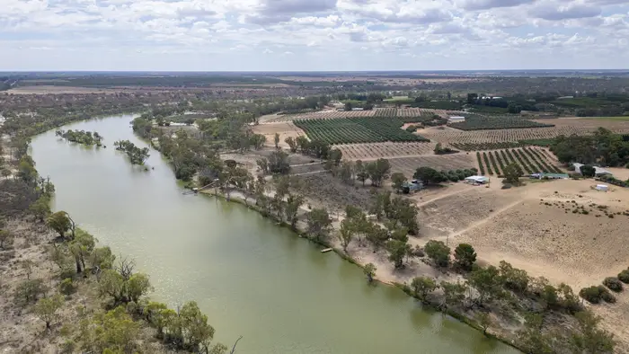 Aerial view over a bend of the River Murray with irrigated orchard blocks and dry ridge country beyond