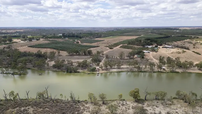 Aerial view of the river channel, sandy banks and river red gums with farmland behind